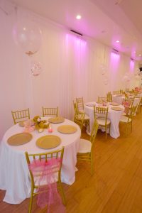 This close-up photo captures the intimate table setup at a Queens baby shower with adorable teddy bear centerpieces, soft lighting, and elegant gold-rimmed plates.