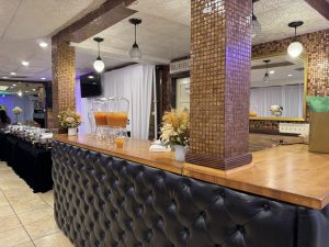 Stylish bar setup with tufted leather details, mosaic tile columns, and fresh floral arrangements — perfect for cocktail hours and receptions.