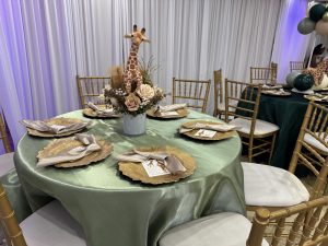 Safari-inspired event décor with emerald green linens, gold tableware, and balloon arrangements — perfect for birthdays and themed celebrations.