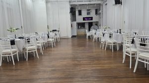 : A modern event space with chic black and white table settings, white Chiavari chairs, and minimalist floral arrangements. Perfect for elegant weddings, milestone birthdays, and private parties.