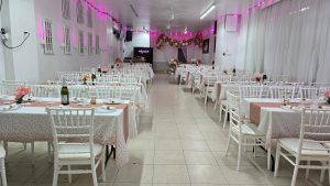 wide-view shot captures the full birthday party setup at Abyss Hall. Rows of beautifully dressed tables with pink runners and gold accents lead to a balloon-decorated backdrop, creating a welcoming and festive atmosphere.