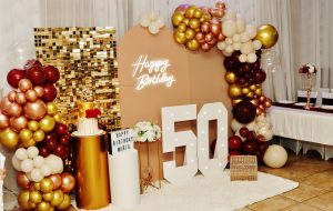 Stunning 50th birthday backdrop with gold balloons and neon signage at Occasions Hall. A beautiful celebration setup perfect for milestone events.
